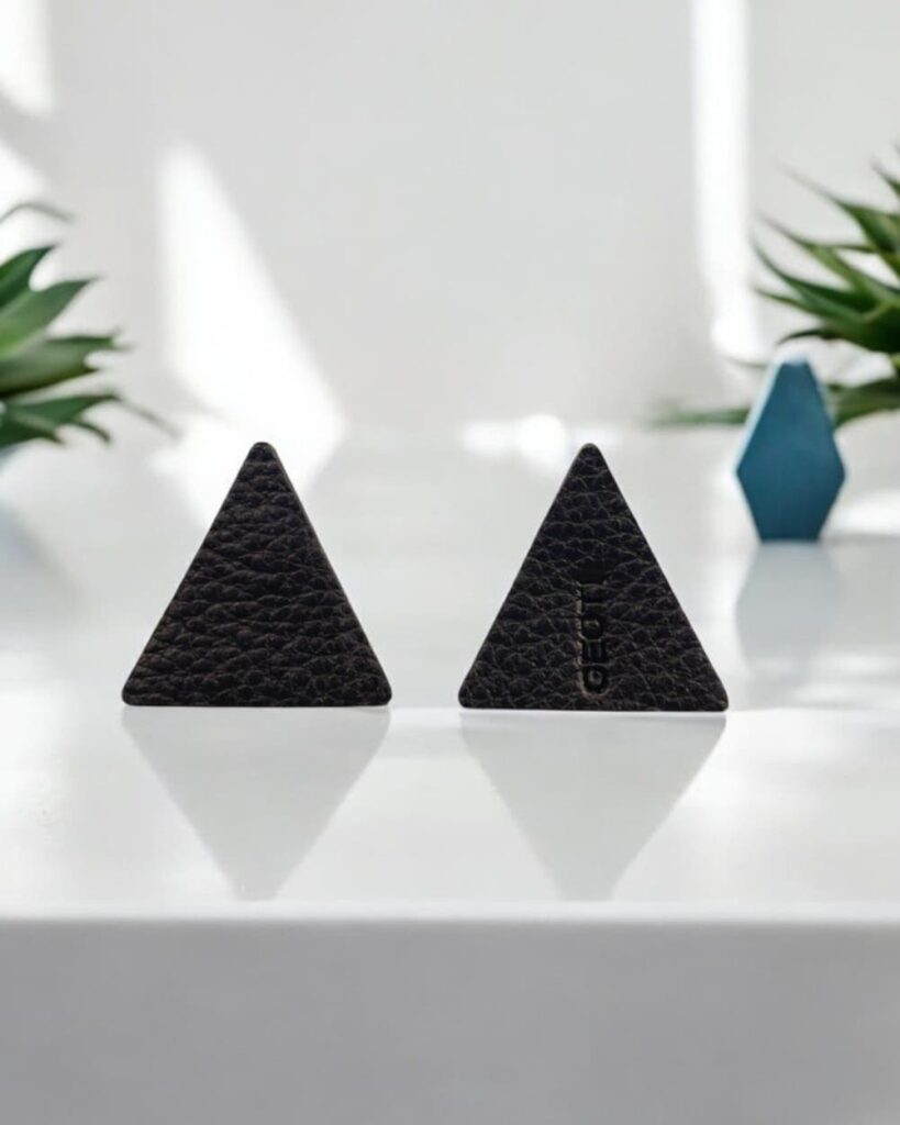 Schwarze Lederohrringe, geometrisches Dreieck, minimalistisch, Unisex. Präsentiert auf hellem Stein.