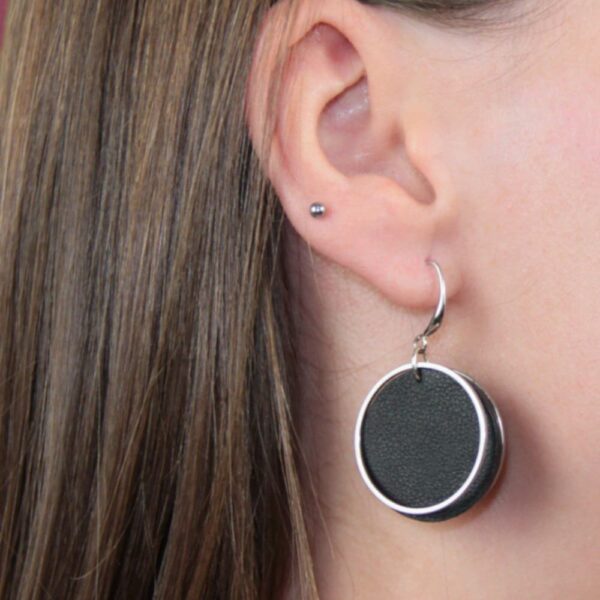 Runde schwarze Lederohrringe mit glänzendem Edelstahlring – handgemachter Ohrschmuck von GEOTI im modernen Look