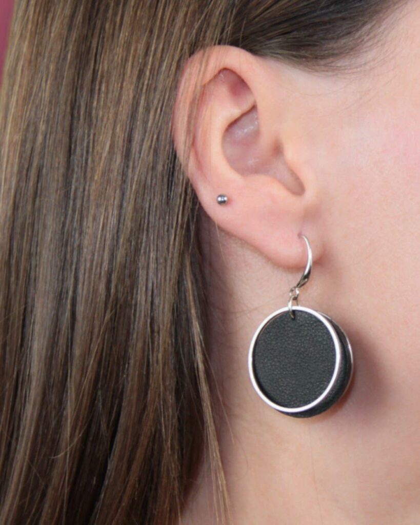 Runde schwarze Lederohrringe mit glänzendem Edelstahlring – handgemachter Ohrschmuck von GEOTI im modernen Look
